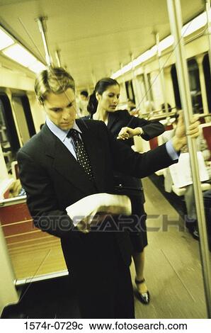 Stock Image - Businessman and a businesswoman standing in a train. Fotosearch