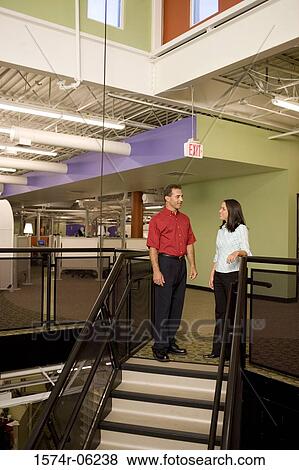 Stock Photo - Businessman and a businesswoman standing on stairs. Fotosearch