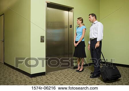 Stock Photograph - Businessman and a businesswoman standing near an elevator. Fotosearch