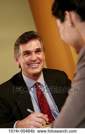 Businessman and a businesswoman talking in an office View Large Photo Image Stock Image - Businessman and a businesswoman talking in an office. Fotosearch