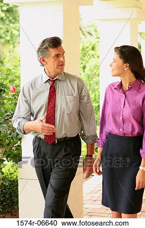 Stock Image - Businessman and a businesswoman walking in a corridor. Fotosearch