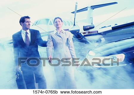 Stock Image - Businessman and a businesswoman walking in an airport. Fotosearch