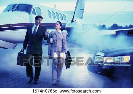 Businessman and a businesswoman walking in an airport View Large Photo Image Stock Image - Businessman and a businesswoman walking in an airport. Fotosearch