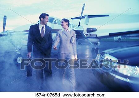 Stock Image - Businessman and a businesswoman walking in an airport. Fotosearch