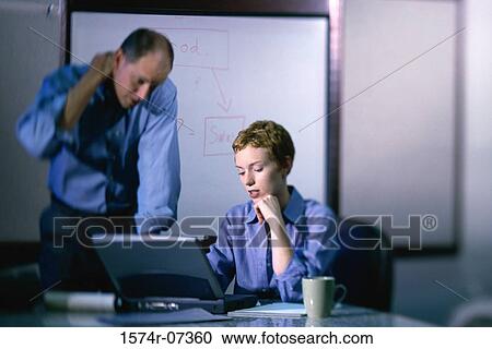 Stock Image - Businessman and a businesswoman working on a laptop. Fotosearch