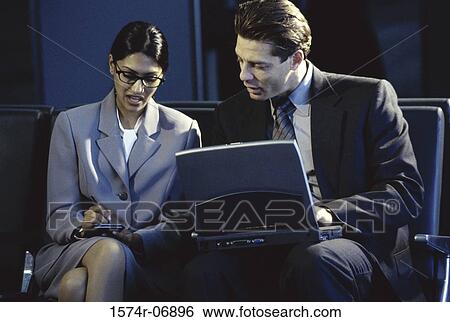 Stock Photograph - Businessman and businesswoman sitting in front of a laptop. Fotosearch