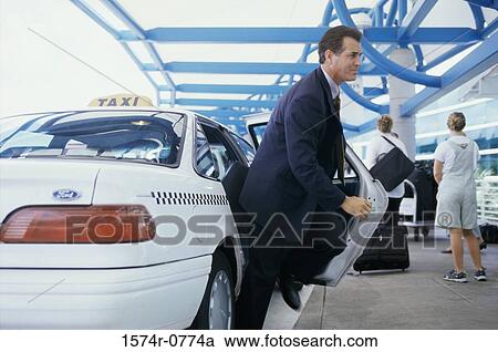 Businessman getting out of a taxi outside an airport View Large Photo Image Stock Image - Businessman getting out of a taxi outside an airport. Fotosearch