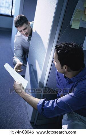 Stock Photography - Businessman handing another businessman documents in an office. Fotosearch