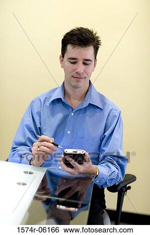 Businessman holding a hand held device View Large Photo Image Stock Photograph - Businessman holding a hand held device. Fotosearch