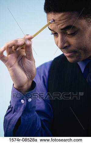 Businessman holding a pencil against his forehead View Large Photo Image Stock Image - Businessman holding a pencil against his forehead. Fotosearch