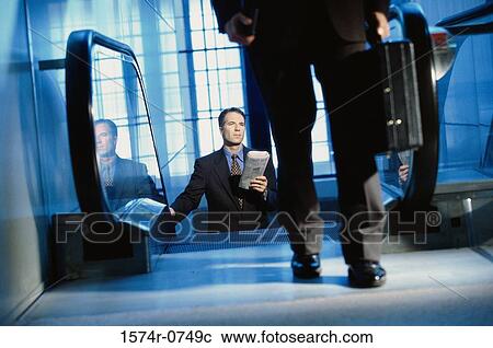 Businessman on an escalator View Large Photo Image Stock Image - Businessman on an escalator. Fotosearch
