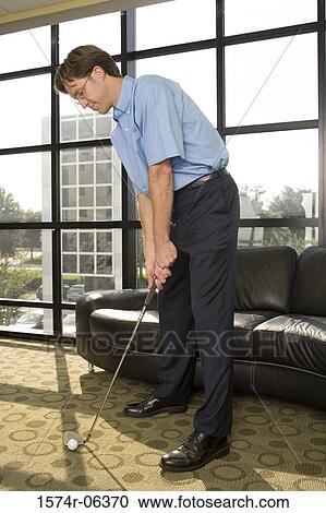 Businessman playing golf in an office View Large Photo Image Stock Image - Businessman playing golf in an office. Fotosearch
