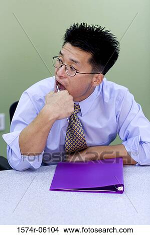 Businessman sitting in an office with a file in front of him View Large Photo Image Picture - Businessman sitting in an office with a file in front of him. Fotosearch