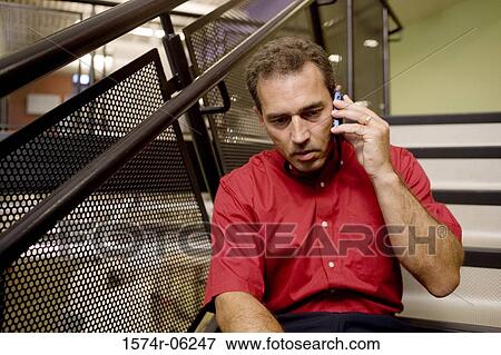 Stock Photo - Businessman sitting on a staircase talking on a mobile phone. Fotosearch