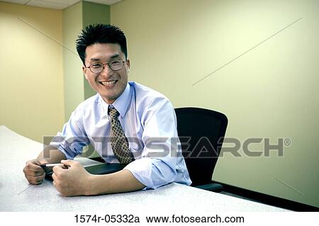 Businessman smiling in an office View Large Photo Image Stock Image - Businessman smiling in an office. Fotosearch
