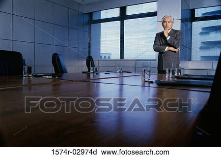 Businessman standing in a boardroom with his hand on his chin View Large Photo Image Stock Image - Businessman standing in a boardroom with his hand on his chin. Fotosearch