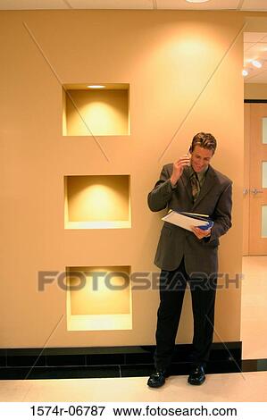Stock Photo - Businessman standing in a corridor using a mobile phone. Fotosearch