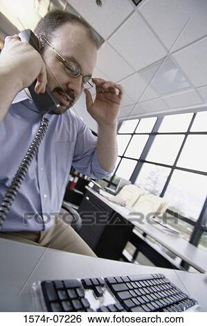 Businessman talking on a landline telephone View Large Photo Image Stock Photograph - Businessman talking on a landline telephone. Fotosearch