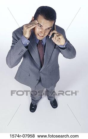 Stock Photo - Businessman talking on a mobile phone with his hand on his head. Fotosearch