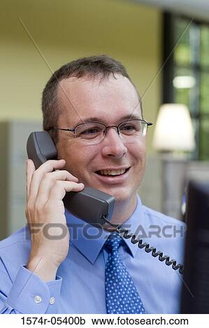Stock Image - Businessman talking on a telephone in an office. Fotosearch