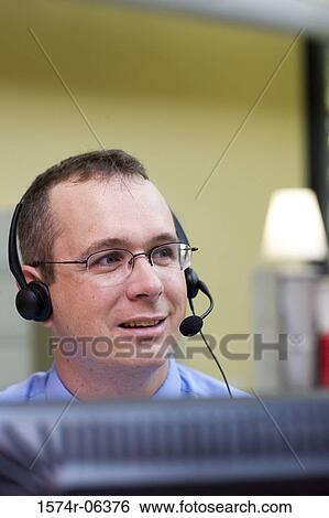 Businessman wearing a headset in an office View Large Photo Image Stock Photograph - Businessman wearing a headset in an office. Fotosearch