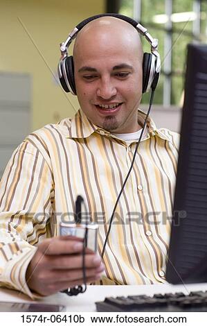 Businessman wearing headphones in an office View Large Photo Image Stock Image - Businessman wearing headphones in an office. Fotosearch
