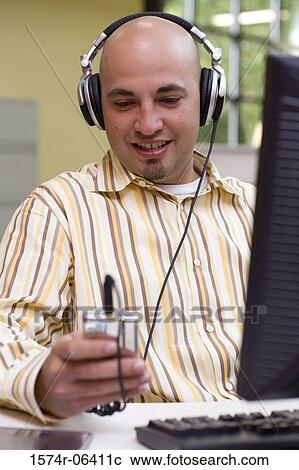 Businessman wearing headphones in an office View Large Photo Image Stock Image - Businessman wearing headphones in an office. Fotosearch