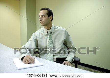Businessman writing on a notepad in an office View Large Photo Image Stock Image - Businessman writing on a notepad in an office. Fotosearch