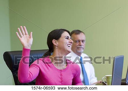 Stock Image - Businesswoman and a businessman sitting in an office. Fotosearch