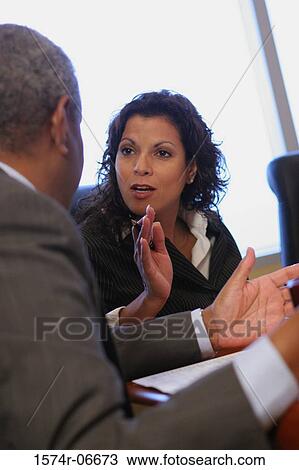 Stock Image - Businesswoman and a businessman sitting in an office. Fotosearch