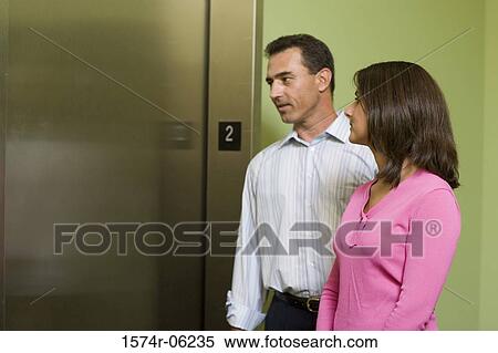 Businesswoman and a businessman standing near an elevator View Large Photo Image Stock Photography - Businesswoman and a businessman standing near an elevator. Fotosearch