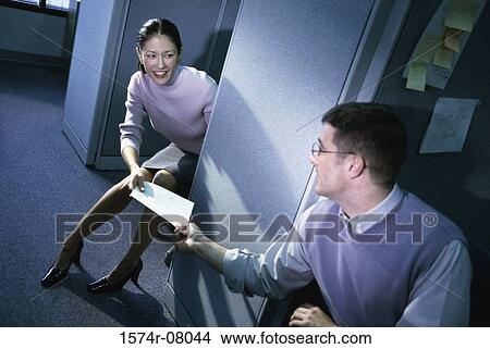 Picture - Businesswoman handing documents to a businessman in an office. Fotosearch
