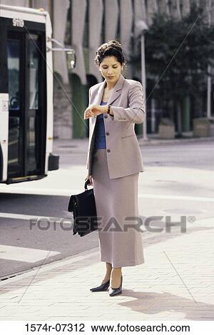 Businesswoman looking at her wristwatch View Large Photo Image Stock Image - Businesswoman looking at her wristwatch. Fotosearch