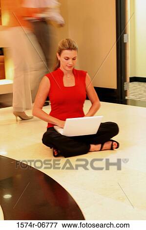 Stock Photo - Businesswoman sitting on the floor working on a laptop. Fotosearch