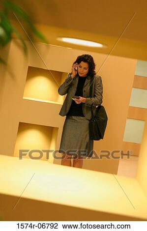 Businesswoman standing in a corridor using a mobile phone View Large Photo Image Stock Image - Businesswoman standing in a corridor using a mobile phone. Fotosearch