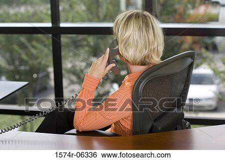 Businesswoman talking on a telephone in an office View Large Photo Image Stock Photograph - Businesswoman talking on a telephone in an office. Fotosearch