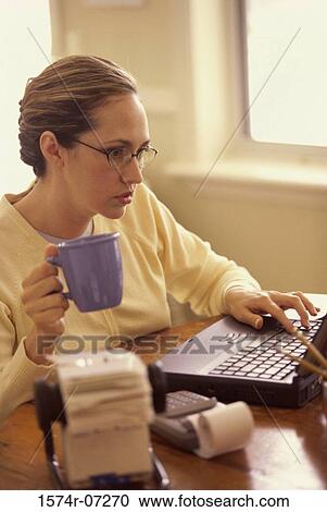 Businesswoman using a laptop and holding a cup View Large Photo Image Stock Image - Businesswoman using a laptop and holding a cup. Fotosearch