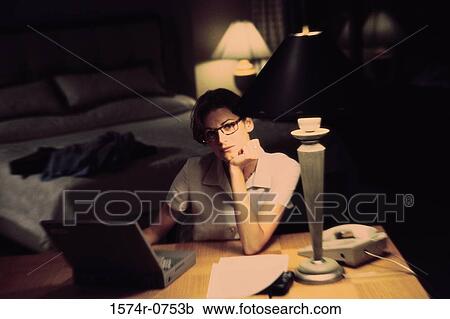 Stock Image - Businesswoman using a laptop with her chin resting on her hand. Fotosearch