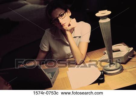 Stock Image - Businesswoman using a laptop with her chin resting on her hand. Fotosearch