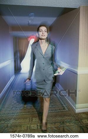 Businesswoman walking in a corridor with a suitcase View Large Photo Image Stock Image - Businesswoman walking in a corridor with a suitcase. Fotosearch