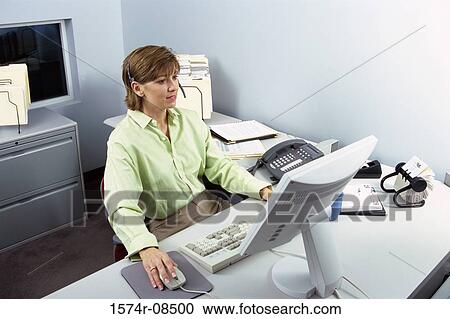 Businesswoman wearing a headset operating a computer mouse View Large Photo Image Stock Image - Businesswoman wearing a headset operating a computer mouse. Fotosearch