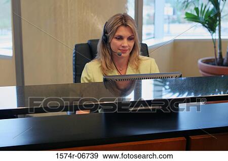 Stock Photo - Businesswoman wearing a headset working on a computer. Fotosearch