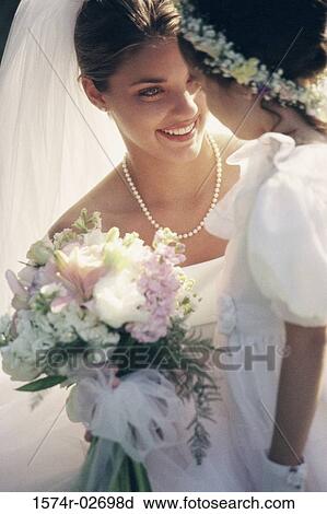 Stock Image - Close-up of a bride smiling at a flower girl. Fotosearch