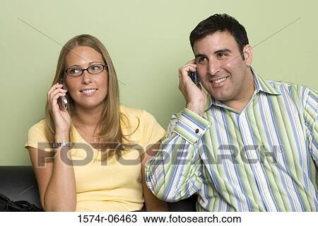 Stock Image - Close-up of a businessman and a businesswoman talking on mobile phones. Fotosearch