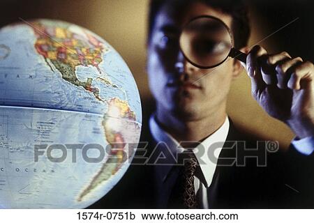 Close-up of a businessman looking at a globe through a magnifying glass View Large Photo Image Stock Image - Close-up of a businessman looking at a globe through a magnifying glass. Fotosearch