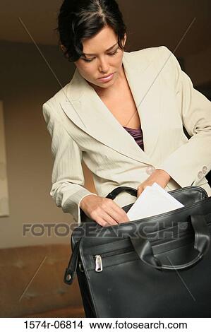 Close-up of a businesswoman putting documents in a bag View Large Photo Image Picture - Close-up of a businesswoman putting documents in a bag. Fotosearch