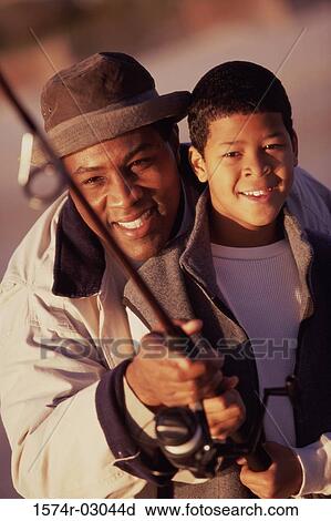 Close-up of a father teaching his son fishing View Large Photo Image Stock Image - Close-up of a father teaching his son fishing. Fotosearch
