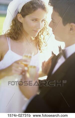 Stock Image - Close-up of a newlywed couple toasting with champagne glasses. Fotosearch