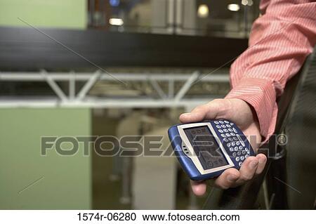 Stock Image - Close-up of a person's hands holding a hand held device. Fotosearch