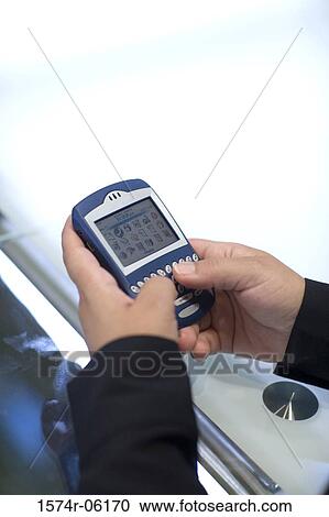 Stock Image - Close-up of a person's hands using a hand held device. Fotosearch